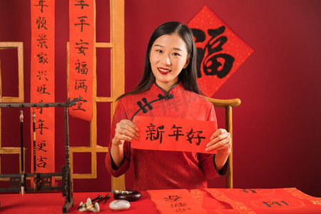 喜庆毛笔字摄影照片_双手拿新年好的女孩子