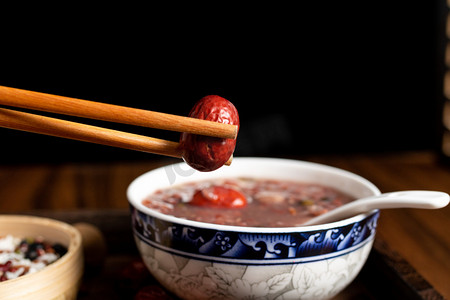 红枣桂圆摄影照片_筷子在腊八粥上夹红枣