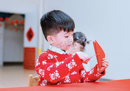 中国小孩摄影照片_手拿剪刀剪纸的小男孩