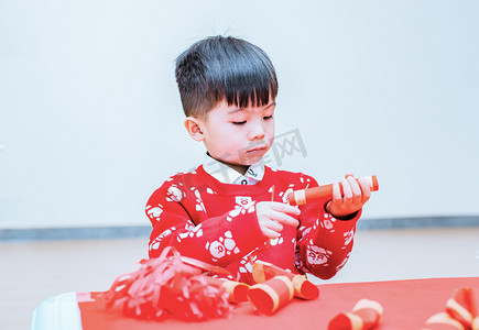 男新年摄影照片_制作鞭炮的男孩子