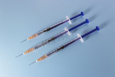 蓝色疫苗摄影照片_蓝色背景前的针剂