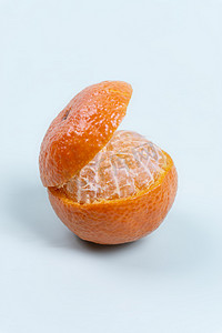 一个新鲜扒皮的橘子在蓝色背景摆拍摄影图配图