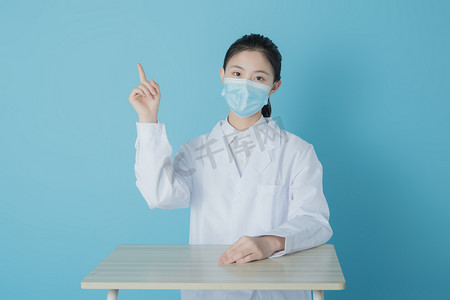 美女医护白天带口罩的女医护室内坐着手指上方摄影图配图