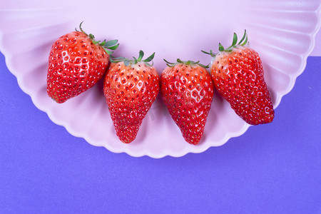 紫色背景粉色盘子红色草莓美味鲜甜水果摄影图配图