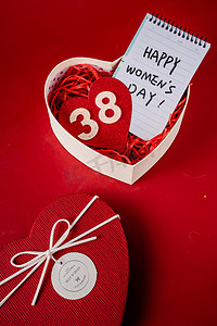 红色背景礼物礼盒摄影照片_三八妇女节心形礼物红色背景摄影图配图