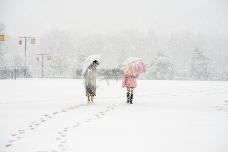 手绘雪地女孩摄影照片_下雪天白天雪地上的小女孩野外雪地上行走摄影图配图