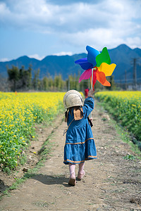 腊八节小孩摄影照片_田野春天下午女孩奔跑油菜花地风车奔跑摄影图配图人物