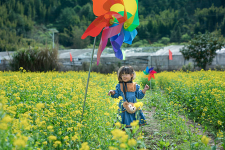 儿童大风车摄影照片_乡村春天下午女孩儿童女童小可爱田野看风车摄影图配图