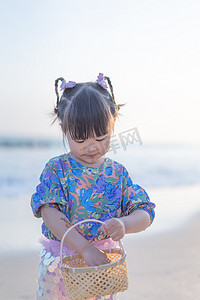 初春沙滩嬉戏的小女孩夕阳女孩海边捡贝壳摄影图配图