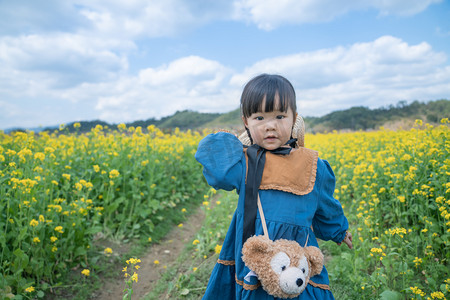 熊女孩摄影照片_春天春天女孩小熊包乡下田野摄影图配图