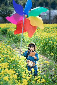 儿童风车摄影照片_乡村春天二月三月油菜花小可爱风车田野玩耍摄影图配图