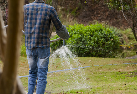 白天户外园艺师在草地上浇水摄影图配图