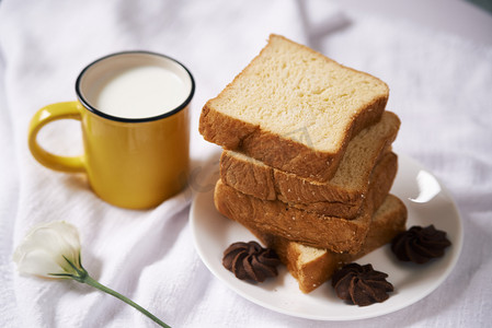 白色欧式边框摄影照片_食物早餐早上面包牛奶白色纯色摆放摄影图配图