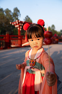 重阳节喜庆摄影照片_展旗峰吃糖葫芦的姑娘夕阳年画娃娃摄影图配图