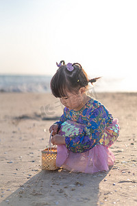 捡贝壳的小女孩夕阳小女孩沙滩捡摄影图配图