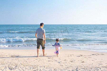 奔跑的爸爸和女儿下午爸爸和女儿沙滩奔跑背影摄影图配图