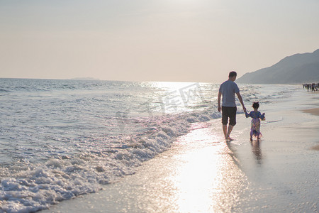 夏天的海边摄影照片_手拉手走远的父女下午父女沙滩手拉手摄影图配图