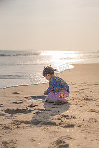 沙滩女孩傍晚女孩背影海边捡贝壳摄影图配图
