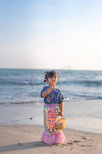 吹螺号的小姑娘下午小女孩沙滩吹螺号摄影图配图
