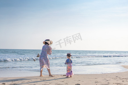 沙滩捡贝壳摄影照片_海边母女下午妈妈和女儿沙滩捡贝壳摄影图配图