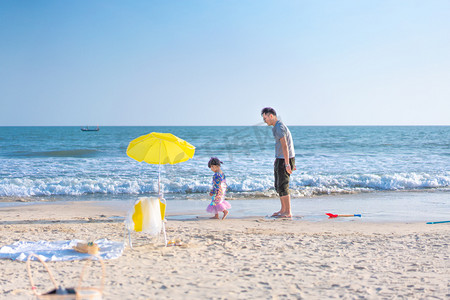 太阳海报素材摄影照片_海边父女侧脸夕阳父女沙滩挖沙摄影图配图