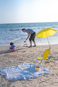 挖沙摄影照片_海边父女下午爸爸和女儿沙滩亲子摄影图配图