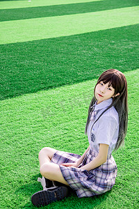 服装背景图摄影照片_日系唯美清晨穿着jk制服的少女足球场坐在草坪上摄影图配图