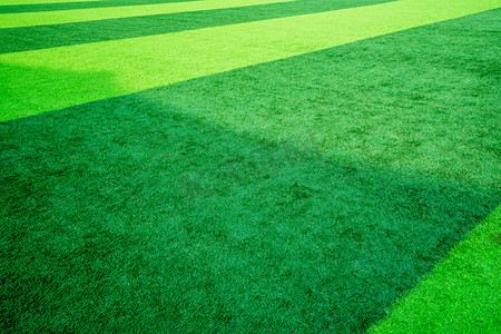 摄影照片_草坪白天绿色草坪足球场踢球摄影图配图