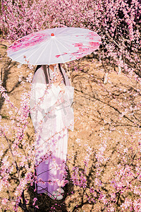 古风美女手桃花园打伞赏花摄影图配图