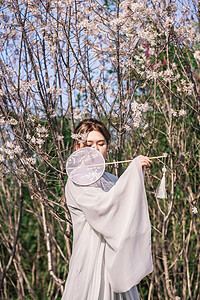 唯美古风桃花摄影照片_古风美女唯美白天古装女孩公园拿扇子摄影图配图