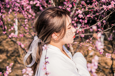 古风美女春天春游桃花园赏花摄影图配图