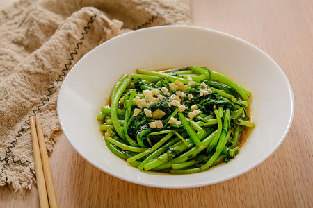 食物菜谱摄影照片_美食白天清炒茼蒿木桌摆放摄影图配图