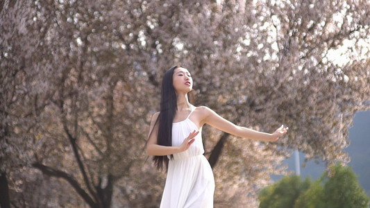 春天阳光明媚美女在樱花树下跳舞