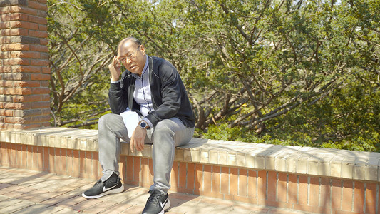 老人独坐在户外头部疼痛揉搓疾病身体不适症状人像