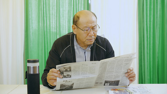 老人看书摄影照片_老年人在家看报纸阅读休闲时光