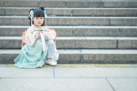 儿童正面摄影照片_穿汉服的小姑娘下午小女孩影视城坐台阶摄影图配图