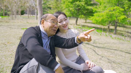 踏青节好饱摄影照片_开春春天父亲女儿坐公园草坪郊游踏青看风景温馨人像