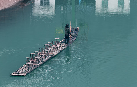红军竹筏摄影照片_竹筏渡河的人下午竹筏湖水无摄影图配图