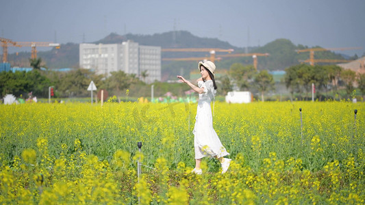 春天白衣少女在油菜花海中漫步郊游