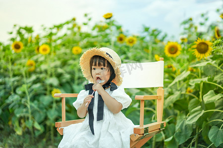 sunflower摄影照片_儿童孩子向日葵女童傍晚女孩户外吃棒棒糖侧面摄影图配图