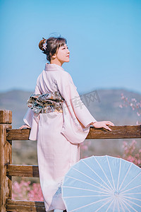 日系文艺小清新摄影照片_文艺日系写真白天和服少女户外木围栏拄着栏杆吹风摄影图配图美女