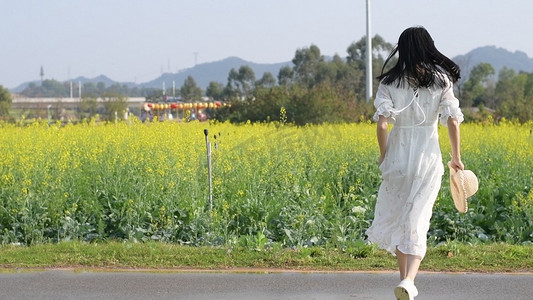 春天白衣少女在油菜花海中奔跑