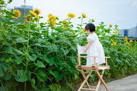 夏季玩耍女孩摄影照片_儿童孩子野餐女孩下午向日葵女孩户外玩耍侧面摄影图配图