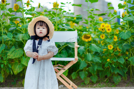 嘟嘴摄影照片_儿童孩子向日葵地的嘟嘴女孩下午小女孩向日葵地嘟嘟嘴摄影图配图