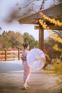 日系文艺小清新摄影照片_文艺日系人像白天和服少女户外公园撑伞低头美女摄影图配图