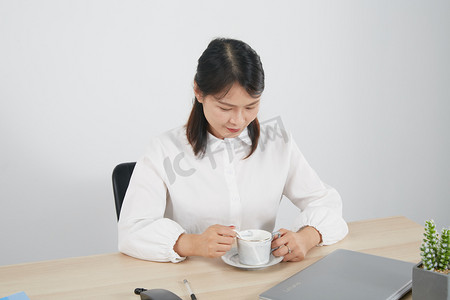 女性职工摄影照片_商务人物上班族上班时喝咖啡摄影图配图
