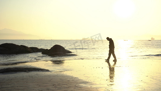 落日夕阳老人行走在逆光海滩剪影
