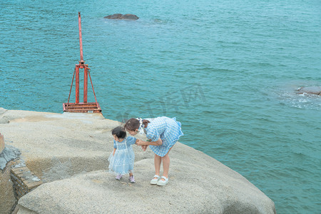 日系摄影照片_亲子装下午妈妈和娃娃海边弯腰摄影图配图
