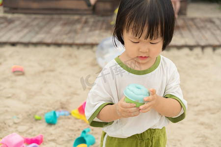 初夏小清新摄影照片_玩沙女孩傍晚女孩沙滩玩沙摄影图配图