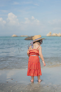 夏季玩耍女孩摄影照片_沙滩女孩夕阳女孩沙滩背影摄影图配图